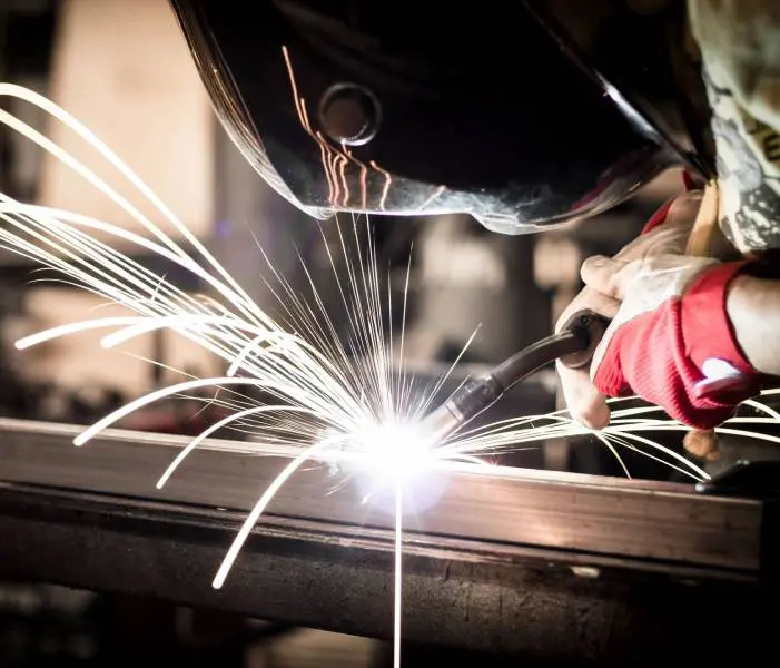 A person welding metal with sparks flying from the side.