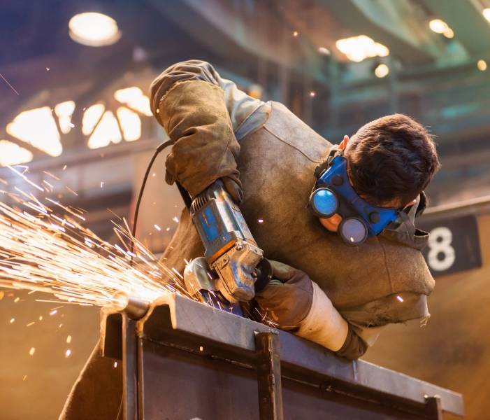 A man wearing protective gear while using an angle grinder.