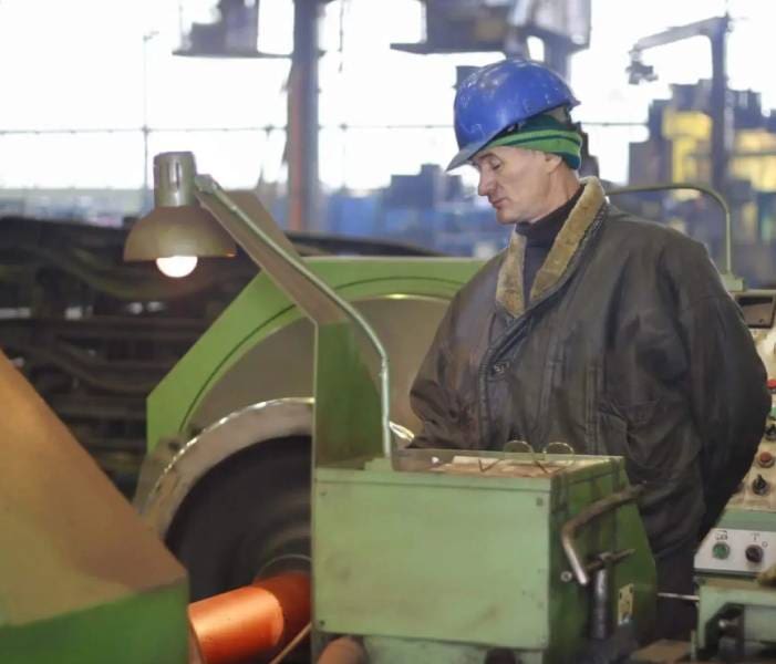 A man in blue hard hat working on machine.