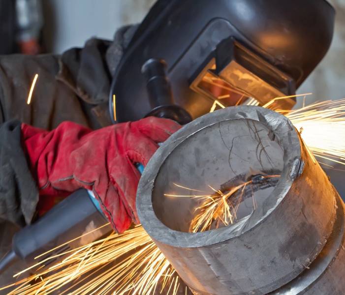 A person wearing protective gear welding metal.