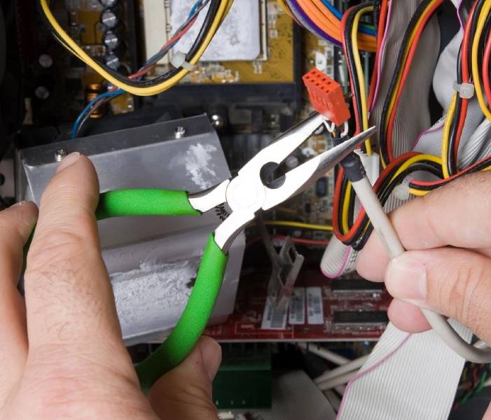 A person holding green pliers and wires in their hand.