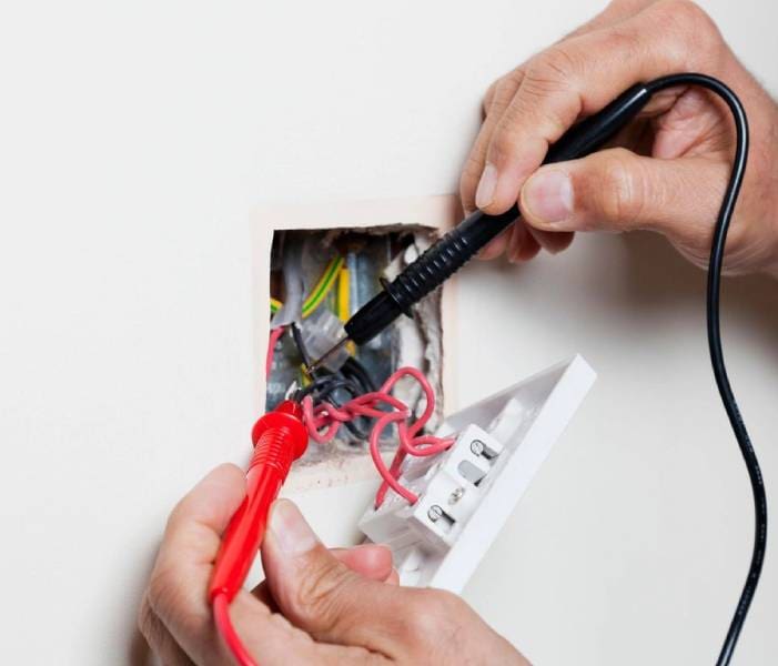 A person is cutting wires in an electrical box.