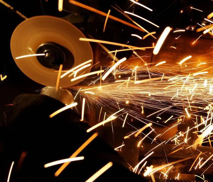 A person is grinding metal with sparks flying from their hands.