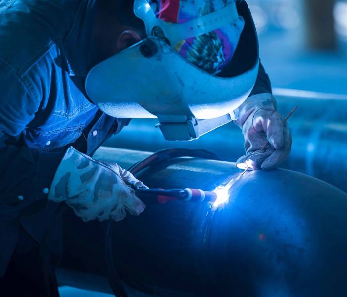 A person welding in the dark with blue light.