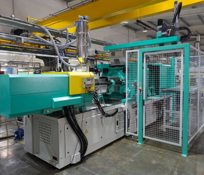 A machine in a factory with wires hanging from the ceiling.