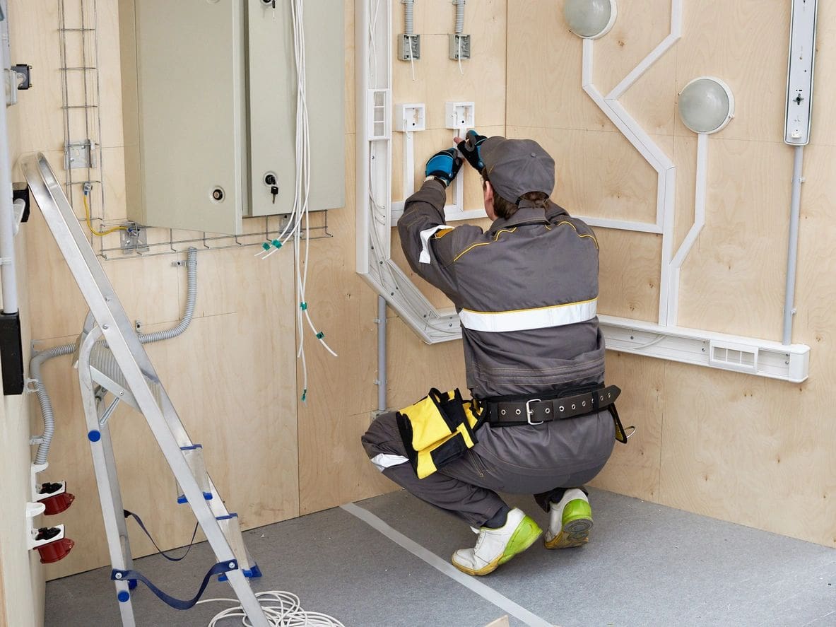 A man in grey work suit working on wall.